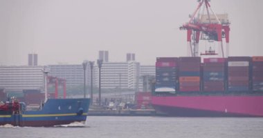 Tokyo Bulutlu Günü 'nde konteynır iskelesinin yanında hareket eden büyük bir gemi. Yüksek kalite 4K görüntü. Koto bölgesi Aomi Tokyo Japonya 05.20.2022 Burası Ooi Konteynır Rıhtımı. Bu onlardan biri.