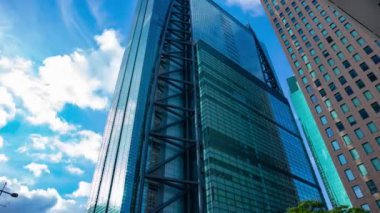 A timelapse of cloud reflecting the building in the business town wide shot tilt. High quality 4k footage. Minato district Shiodome Tokyo Japan 07.25.2022 Here is a center of the city in Tokyo. 