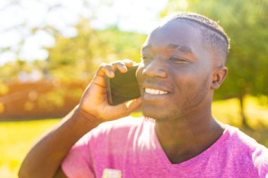 Yakışıklı Latin adam, güneşli yaz günbatımında telefonla konuşuyor.