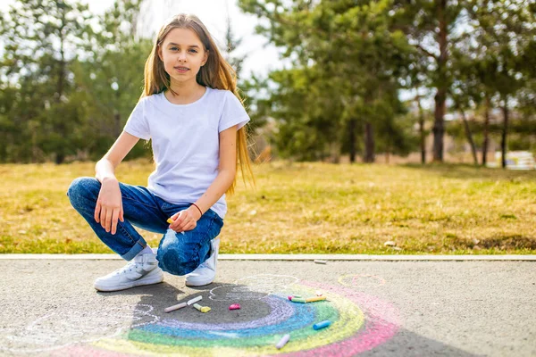 Adolescente dibujo de una tiza de color arco iris en el asfalto en el día de verano — Foto de Stock