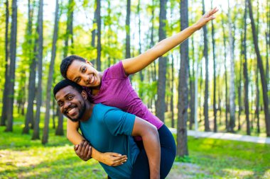 Mutlu genç adam ormanda güzel kadınını sırtında taşıyor.