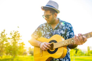 Yakışıklı Hintli adam yaz parkında gitar çalmaya başladı.