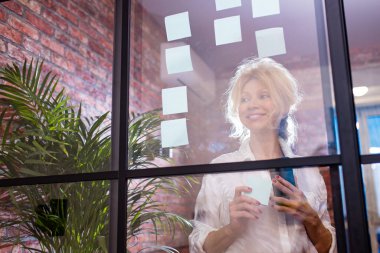 Çekici orta yaşlı bir kadın mükemmel bir gülüşle cama yapıştırıcı yapıştırdı.