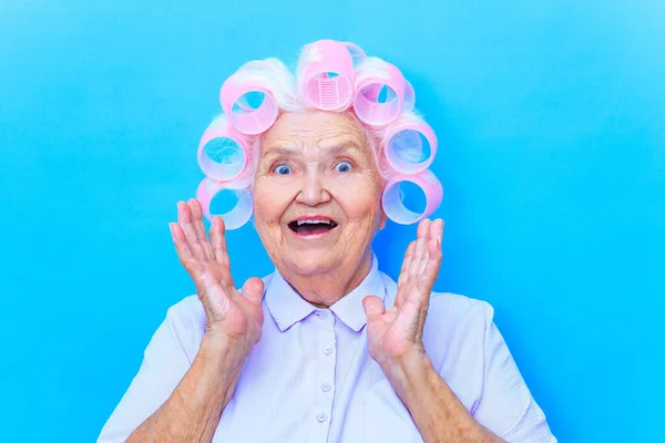 Charmig gammal kvinna med papiljotter på vit grå hår skjorta gör sig redo för datum isolerad på brigth blå bakgrund — Stockfoto