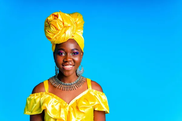 Afrikanerin mit gelbem Seidenturban und silbernen Ohrringen und Nasenpiercing im blauen Studiohintergrund — Stockfoto