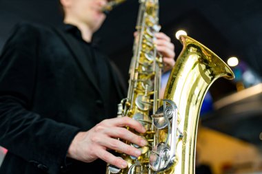 Saksafon elinde, siyah kıyafetli adam.