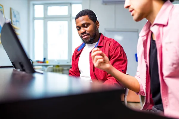 Latin hispanic man learning to play on piano with caucasian teacher in classroom — Stock Photo, Image