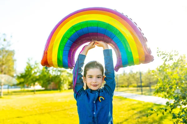 Niedlichen kleinen brünetten Mädchen hält eine Luft bunten Regenbogen-Ballon im Sommer Park — Stockfoto