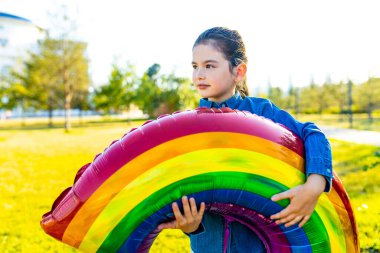 Güzel Latin Latin 7 yaşında, yaz parkında gökkuşağı balonuyla gezen bir kız.