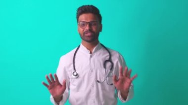 Hintli sakallı kardiyolog, gözlüklü, beyaz ceketli, steteskoplu, mavi stüdyo geçmişli, iyi bir haber veriyor.