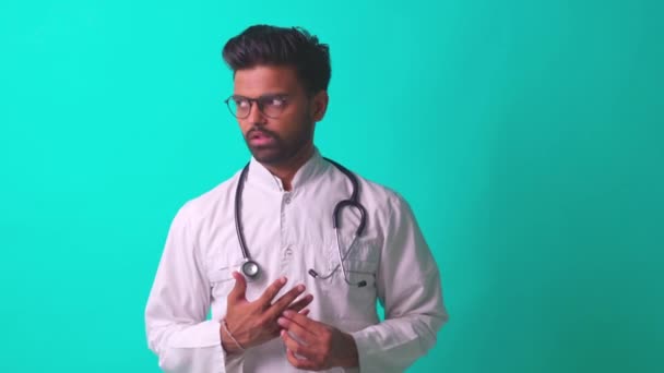 Young latin hispanic medican man wear eye glasses with stethoscope telling bad news in blue studio wall background — Stock Video