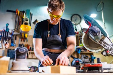 Atölyede tahtayla çalışan yakışıklı marangozun portresi