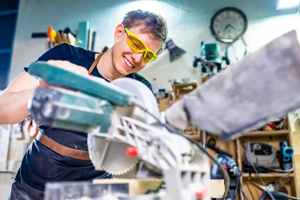 Portret van knappe timmerman werkend met plank in werkplaats — Stockfoto