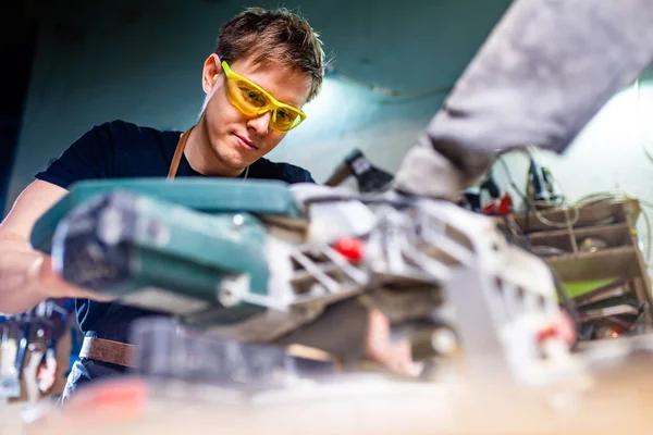 Portret van knappe timmerman werkend met plank in werkplaats — Stockfoto