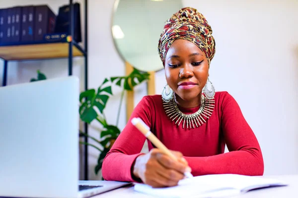 Bild einer Afroamerikanerin mit Turban über dem Kopf mit Laptop im Büro — Stockfoto