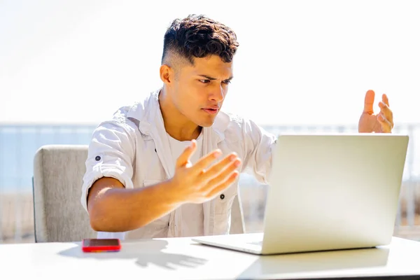 Joven hombre freelance en camisa blanca trabajando por ordenador portátil en la cafetería de playa — Foto de Stock