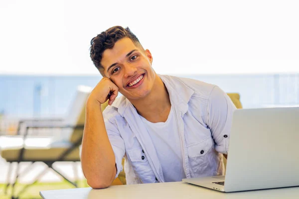 Freiberuflicher junger Mann in weißem Hemd arbeitet mit Laptop im Strandcafé — Stockfoto