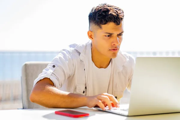 Feliz estudiante argentino pecando con laptop al aire libre y luciendo contento — Foto de Stock