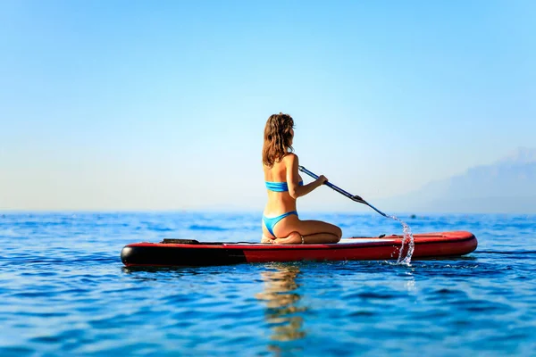 Deportista fitness mujer en SUP bordo en soleado agradable día en el mar — Foto de Stock