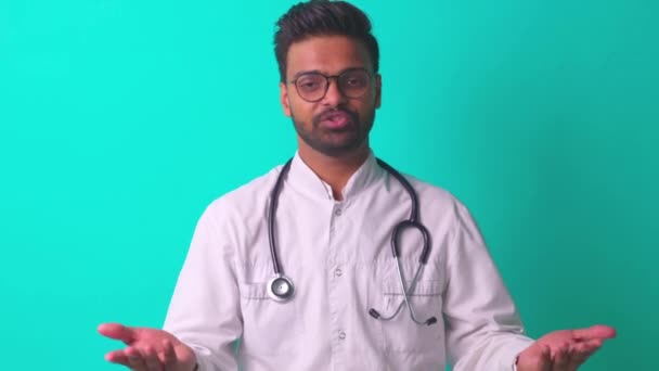 Joven hispano latino hombre medico usar gafas de ojo con estetoscopio en fondo de pared estudio azul — Vídeos de Stock
