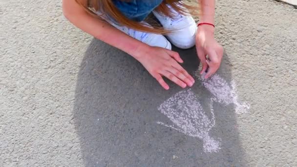 Genç kız yaz günü asfalta gökkuşağı renkli tebeşir çiziyor. — Stok video