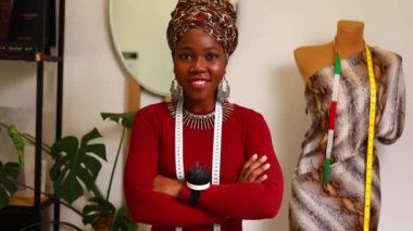 Terzi atölyesinde sarıklı ve gümüş renkli mücevherli Afro-Amerikan kadın.