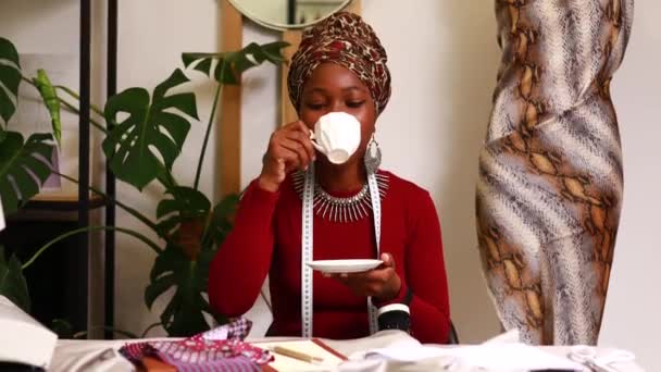 Mulher tanzaniana com turbante impressão de cobra sobre ouvir trabalhar na casa de moda — Vídeo de Stock