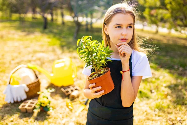 Gadis remaja dengan celemek hitam berkebun di kebun belakang — Stok Foto
