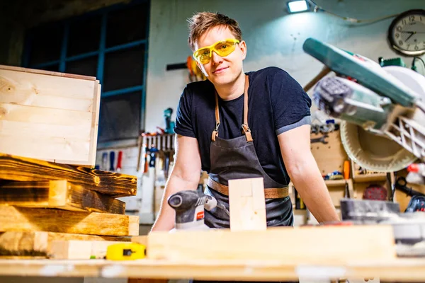 Portret van knappe timmerman werkend met plank in werkplaats — Stockfoto