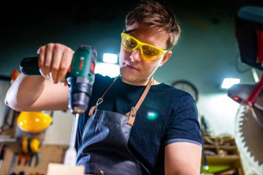 Marangoz genç, atölyede ahşapla çalışıyor.