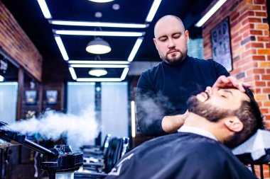 Berber dükkanında berbere saçını kestiren İspanyol sakallı adam.