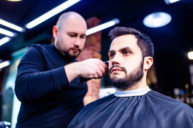 Berber dükkanında berbere saçını kestiren İspanyol sakallı adam.