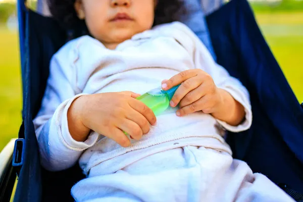 Afroamericana niña sosteniendo un ntibacterial gel en verano parque al aire libre —  Fotos de Stock