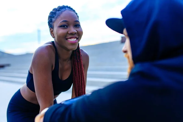 Spanierin mit Afro-Zöpfen, Crossfit-Trainerin, die ihren Freund zum morgendlichen Joggen im Freien motiviert — Stockfoto
