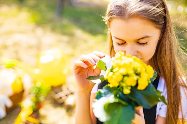 Hermosa colegiala adolescente pasar tiempo al aire libre en el jardín smellind las flores — Foto de Stock