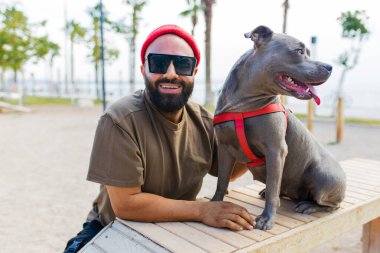 Gözlüklü neşeli melez adam, Osity Park 'ta köpeğiyle oynuyor.