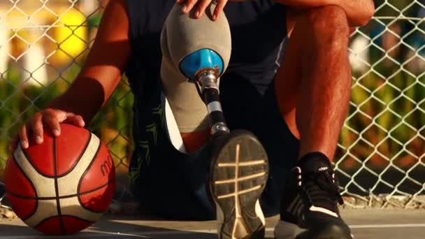 Uomo con protesi alle gambe che gioca a basket nel lato tropicale del mare al tramonto — Video Stock
