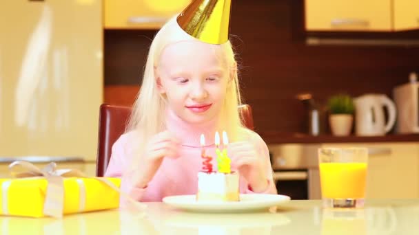 Blond liten flicka med födelsedagstårta hemma blåser ett ljus — Stockvideo