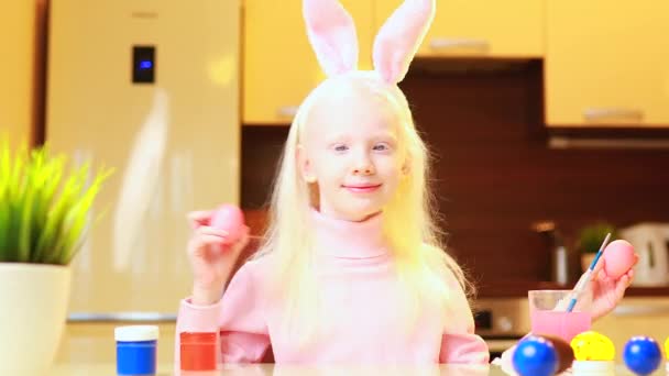 Aranyos kislány festmény húsvét tojás visel nyuszi fülek a konyhában — Stock videók