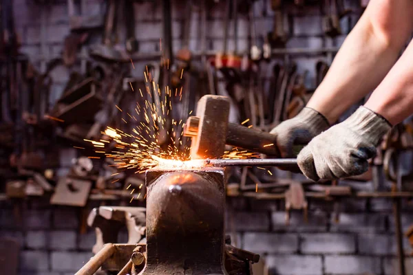 Hiteles kovács ember kovácsol egy fém termék sötét beltéri stúdió — Stock Fotó