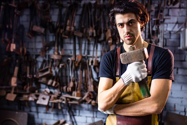 Un auténtico herrero forja un producto metálico en un oscuro estudio interior —  Fotos de Stock