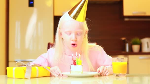 Blonde little girl with birthday cake at home blowing a candles — Stock video