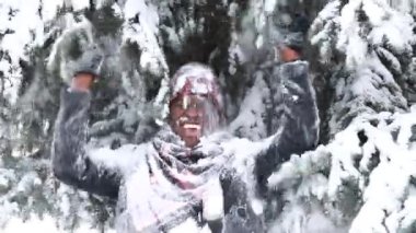 Karlı bir kış ormanında ladin ve köknar ormanlarından kar taneleri düşen Afro-Amerikan bir adam.