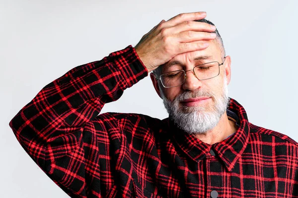 Retrato de hombre maduro aislado sobre fondo gris que sufre de dolor de cabeza severo, cerrando los ojos para aliviar el dolor —  Fotos de Stock