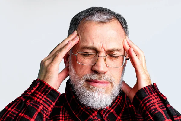 Retrato de hombre maduro aislado sobre fondo gris que sufre de dolor de cabeza severo, cerrando los ojos para aliviar el dolor —  Fotos de Stock