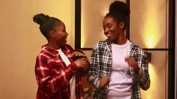 Две счастливые сестры танцуют в гостиной вечером — стоковое видео