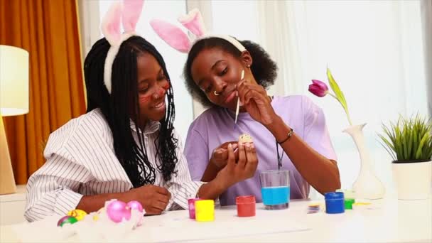 Tavşan kulaklı iki mutlu kız kardeş evde yumurta boyuyor Paskalya 'ya hazırlanıyor. — Stok video