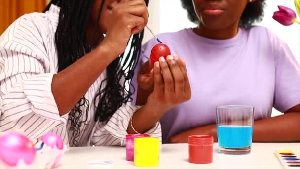 Multirracial duas mulheres pintando ovos com bonito rosa coelho trajes orelhas no apartamento — Vídeo de Stock