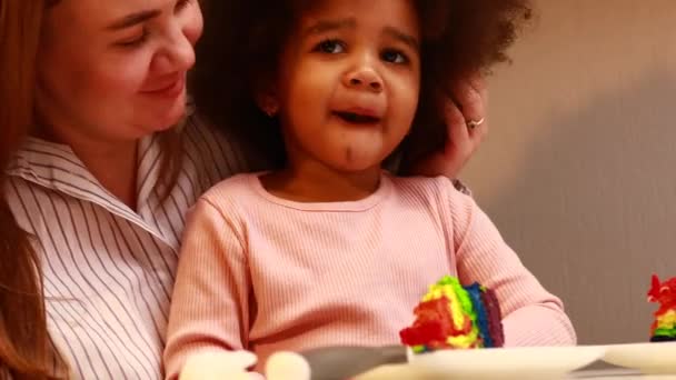 Glückliche multiethnische Familie isst Regenbogenkuchen in der Küche — Stockvideo