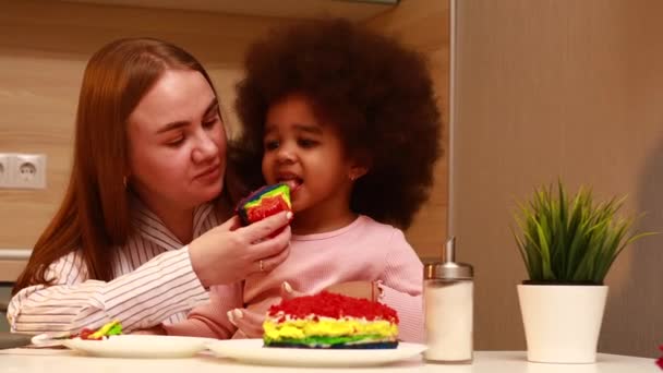Щаслива багатоетнічна сім'я їсть веселковий торт на кухні — стокове відео